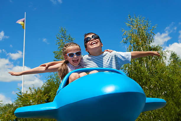 kind und frau fliegen auf flugzeug attraktion in vergnügungspark - park and ride stock-fotos und bilder