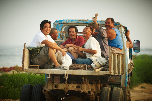 Qinhagdao, China - july, 22, 2010: Old broken truck transporting fishermen in their village. People in the car happy, despite the poverty.