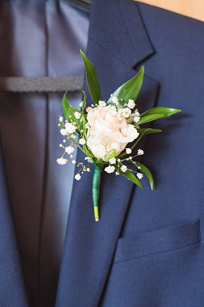 istock White rose boutonniere pinned to a grooms jacket. 590134708