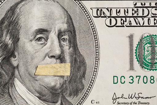 Silente president, portrait of the American leader Benjamin Franklin with mouth closed on the banknote of one hundred dollars, as a symbol of the instability of the modern economy