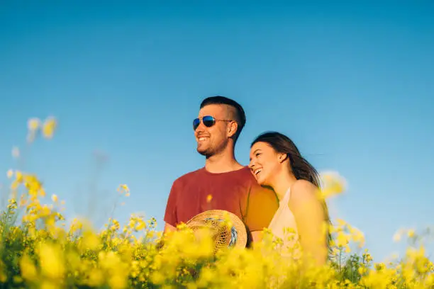 Young couple in rapeseed field in summer, hugging and kissing in casual clothing on sunny day. Image taken with Nikon D800 and professional Nikon lens, developed from RAW in XXXL size. Location: Novi Sad, Serbia, Central Europe, Europe