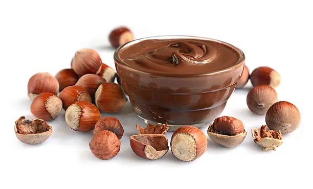 Homemade hazelnut spread in glass bowl with nuts isolated on a white