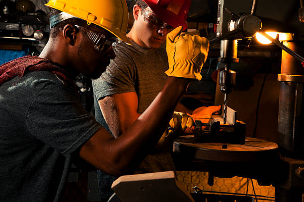 istock Young adult mechanics in small business repair, workshop using press. 590138700
