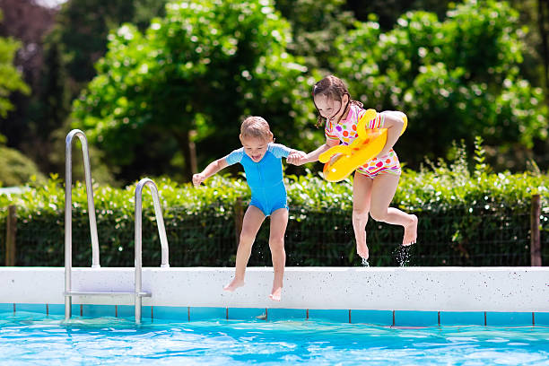 istock Kids jumping into outdoor swimming pool 590139202