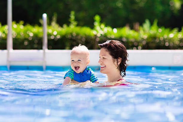 istock Mother and baby playing in swimming pool 590139802