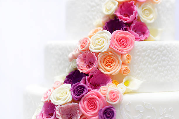 White wedding cake decorated with sugar flowers Detail of a white wedding cake decorated with pink sugar flowers wedding cake close up macro stock pictures, royalty-free photos & images