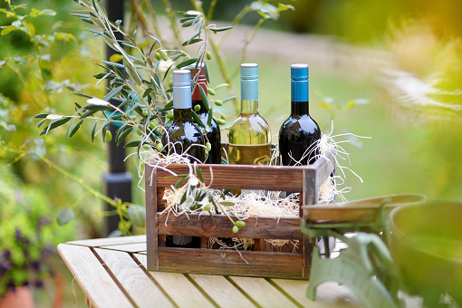 Wine bottle in a vintage wooden crate decorated with olive branches