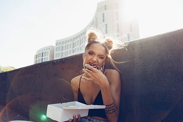 도넛을 먹는 재미있는 아름다운 소녀의 초상화 스톡 사진