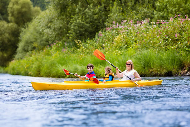 szczęśliwa rodzina korzystających z jazdy kajakiem na rzece - summer camp child teenager kayak zdjęcia i obrazy z banku zdjęć