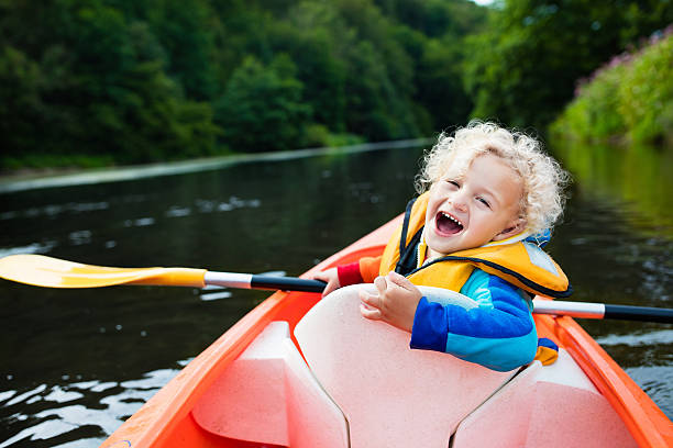 Funny little boy in kayak Happy kid enjoying kayak ride on beautiful river. Little curly toddler boy kayaking on hot summer day. Water sport and camping fun. Canoe for children. Funny child with vessel in a boat. canoeing stock pictures, royalty-free photos & images