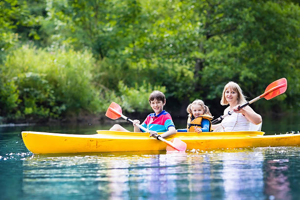 rodzina korzystających z jazdy kajakiem na rzece w letni dzień - summer camp child teenager kayak zdjęcia i obrazy z banku zdjęć