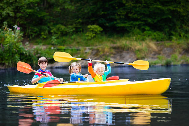 crianças andando de caiaque em um rio no dia quente do verão - summer camp child teenager kayak - fotografias e filmes do acervo