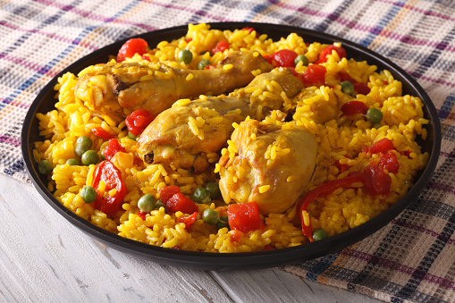 Spanish paella with chicken and vegetables close up on a plate. horizontal