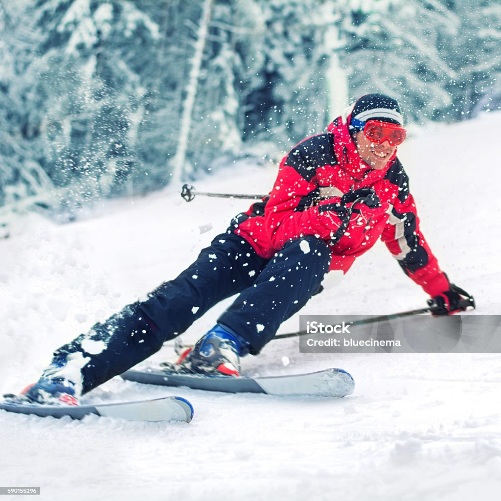 Skiing action Young men snow skier, equipped with modern carving ski equipment. Skiing with a smile enjoying on ski resorts. Skiing carving at high speed, chunks of snow flying. Snow in the foreground. Ski Stock Photo