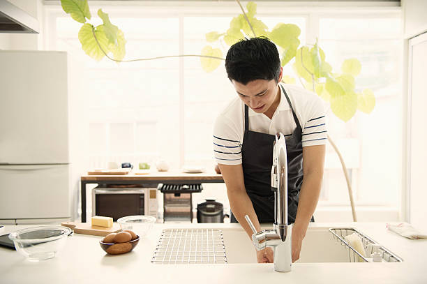 Young man washing the dishes in the kitchen