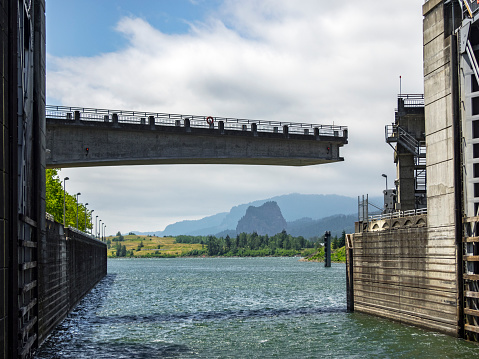 Bonneville Dam Navigation Lock on Oregon side. Downstream lock gates are open and in low water position. The dam's road bridge in a semi closed position. Picture taken from the Columbia River. This dam is located in the Columbia River, the division between the State of Oregon and Washington.