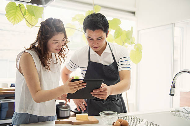 istock Young couple looking at the recipes in the digital tablet 590156568