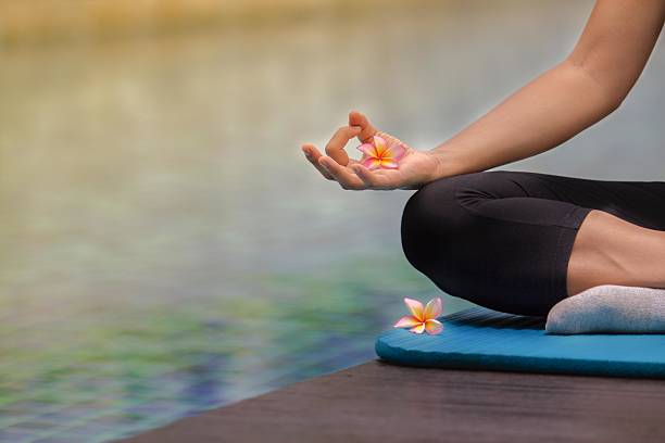 Woman meditating at pool side