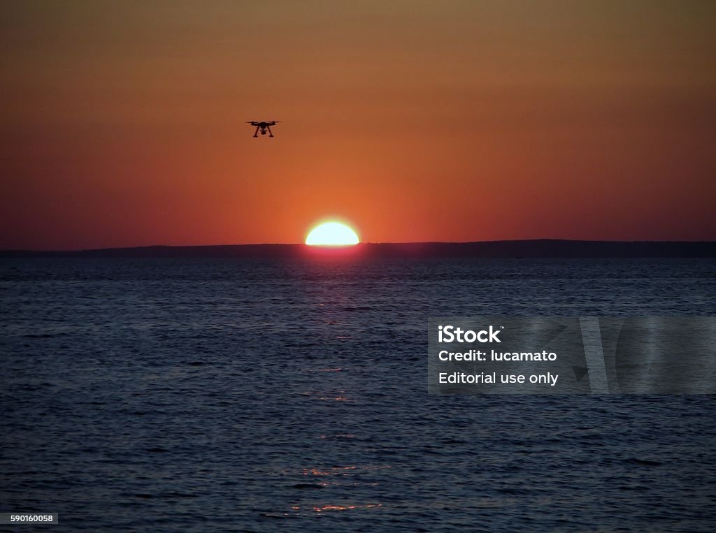 Drone at sunset Sant'Isidoro, Nardò, Lecce, Puglia, Italy - July 21, 2016: a remote-controlled drone, equipped with a camera for overhead shots, while hovering over the sea at sunset. Airplane Stock Photo