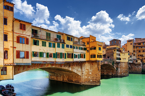 Side view of medieval stone bridge Ponte Vecchio over the Arno River in Florence, Tuscany, Italy. View from the Lungarno degli Archibusieri. Florence is a popular tourist destination of Europe.