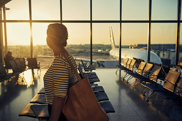 Plane Making her way to the gate Shot of a young woman walking with her luggage through the departure lounge of an airport airport terminal stock pictures, royalty-free photos & images