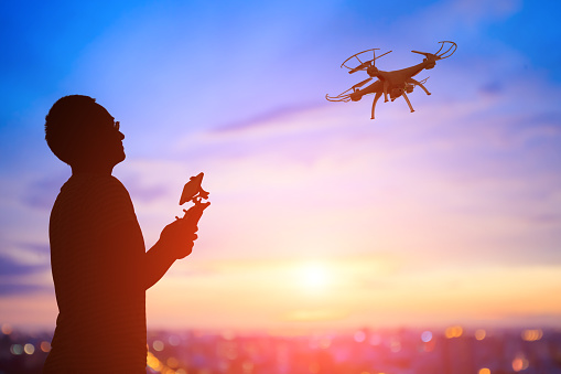 silhouette of man play drone in the sunset, asian