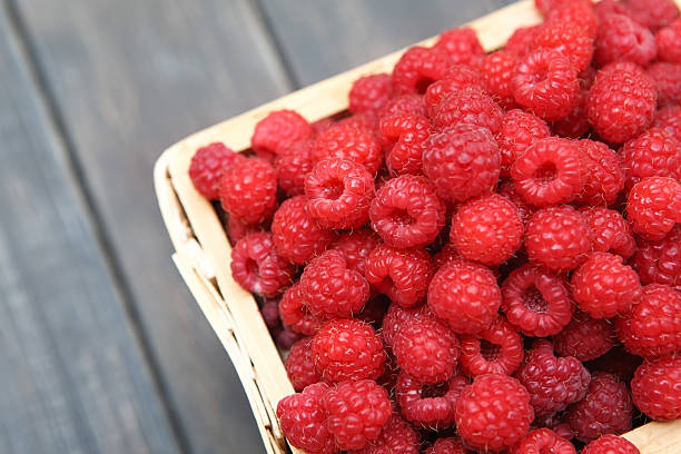 istock Red fresh raspberries basket on brown rustic wood background 590167008