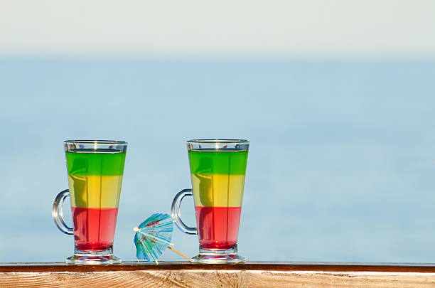 due bicchieri con cocktail colorati sullo sfondo del mare - umbrella two objects cocktail drink foto e immagini stock