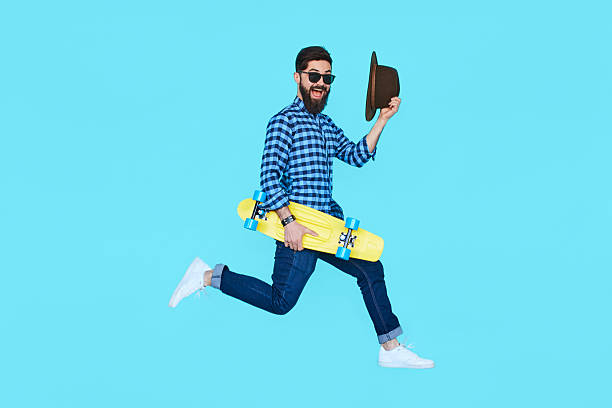 Pretty young bearded man jumping with yellow skateboard