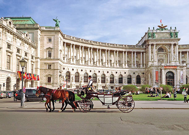 Vienna, Austria - March 21, 2014 : Hofburg palace and square view, people walking and fiaker with white horses in Vienna, Austria