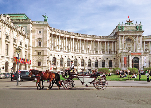 Vienna, Austria - March 21, 2014 : Hofburg palace and square view, people walking and fiaker with white horses in Vienna, Austria
