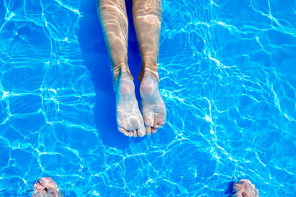 istock Young womans legs in swimming pool. Summer heat. 590173582