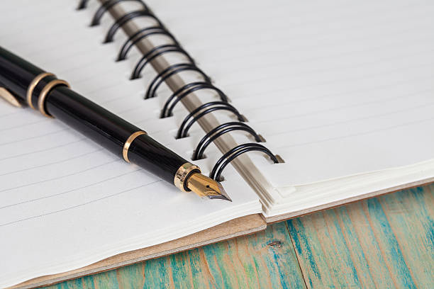 istock selective focus of the  pen on opened lined diary book , 590174646