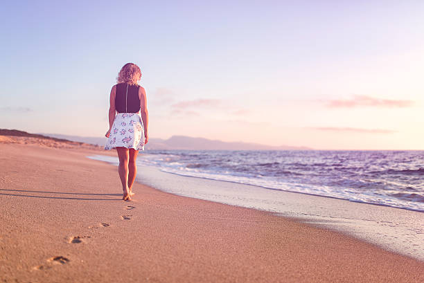 istock Young woman walking on beach at sunset 590176244
