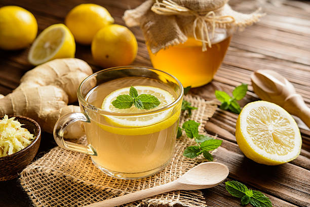 Ginger root tea with lemon, honey and mint Cup of ginger root tea with lemon, honey and mint on a wooden background ginger stock pictures, royalty-free photos & images