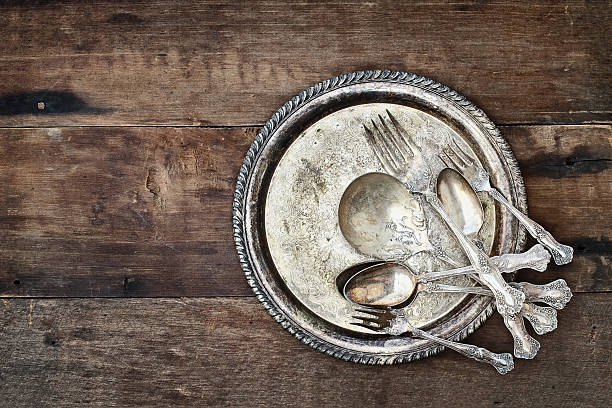 Antique silverware and plate over a rustic old wooden background. Image shot from overhead.