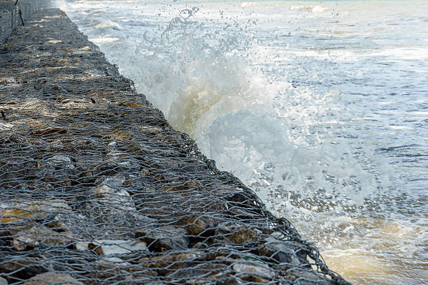 Waves crash into long stone seawall stock photo