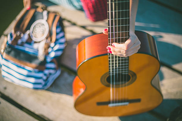 istock young woman sitting on pier and playing guitar 590243514