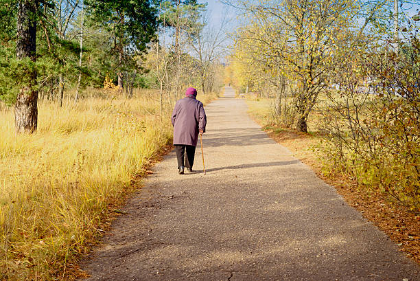 istock Lonely elderly woman walks in autumn park 590245800