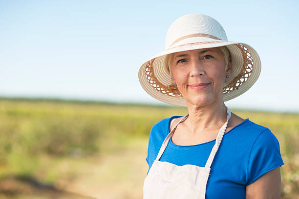 exitosa mujer mayor con sombrero mirando a la cámara - planting clothing gray hair human age fotografías e imágenes de stock