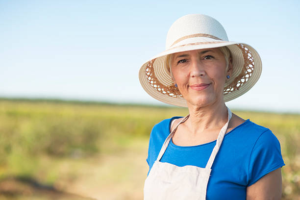 donna anziana di successo con cappello che guarda la macchina fotografica - planting clothing gray hair human age foto e immagini stock