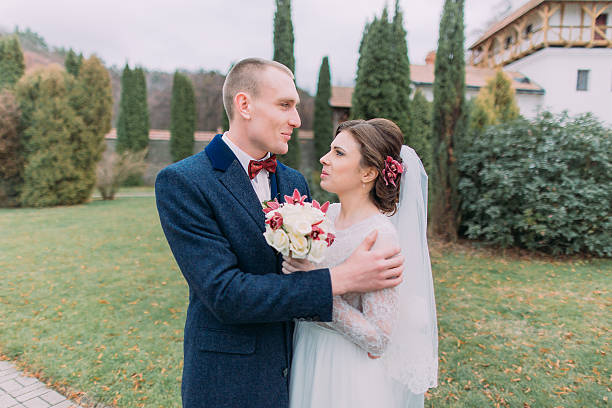 istock Handsome groom tenderly embracing his lovely new wife while both 590248128