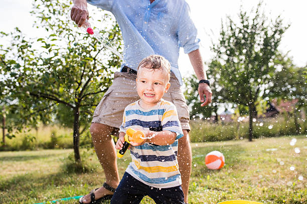 istock Little boy with father playing with water guns, splashing 590248826