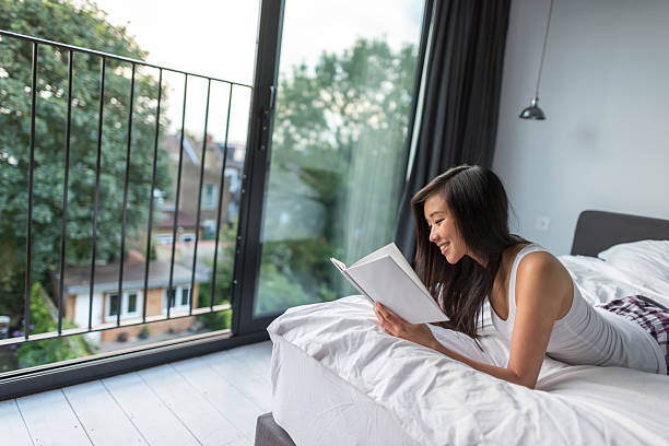 istock Young Asian woman reading in bed 590250802