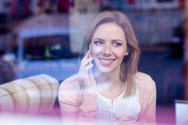 Woman in cafe drinking coffee, making a phone call