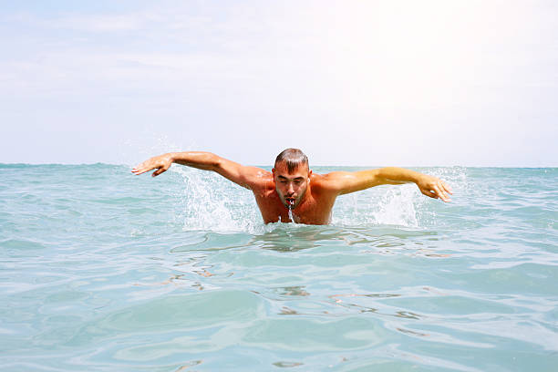 istock Man doing butterfly strokes at sea. 590256378
