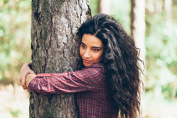 istock Young woman embracing a tree in sunny park 590256530