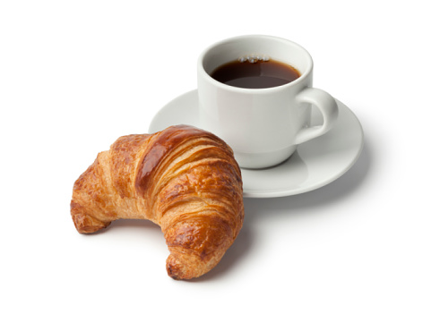 Fresh baked croissant and a cup of coffee on white background