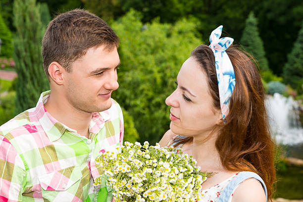 istock Young couple with bouquet flowers looking at each other 590264642