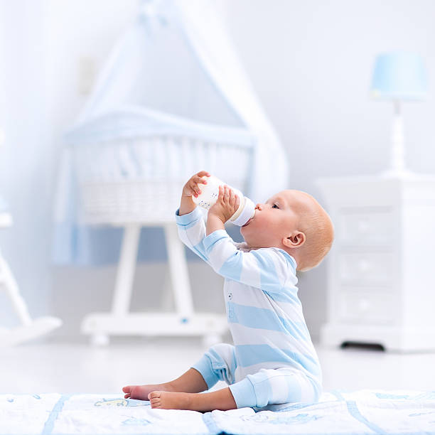 istock Sweet baby boy drinking milk in sunny nursery 590267364